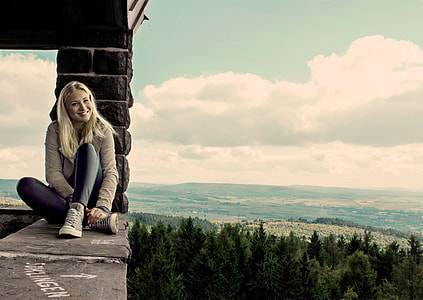 photography of woman sitting on tower near tall trees thumbnail