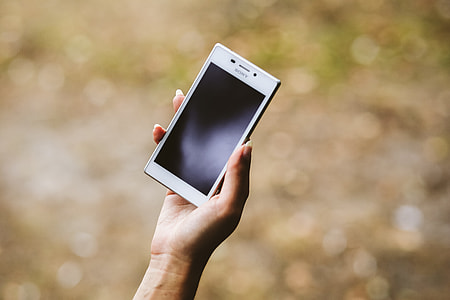 Young woman holding the white mobile phone thumbnail