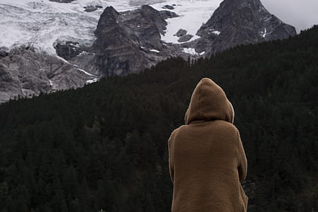 person in brown hoodie sitting in front of forest thumbnail