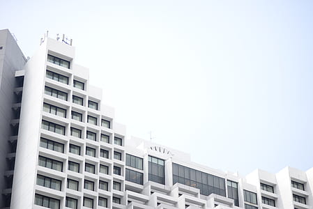 low angle photo of white concrete building under gray sky during daytime thumbnail