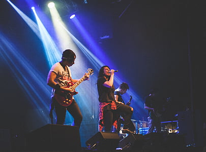 woman holding microphone beside man playing guitar with stage lights on thumbnail