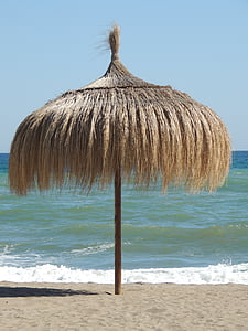 brown umbrella hut on shore during daytime thumbnail
