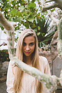 selective focus photography of woman wearing pink and white striped shirt behind tree branch thumbnail