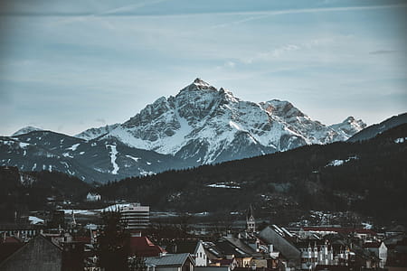 Snow Covered Mountain Near Village Under Blue Sky thumbnail