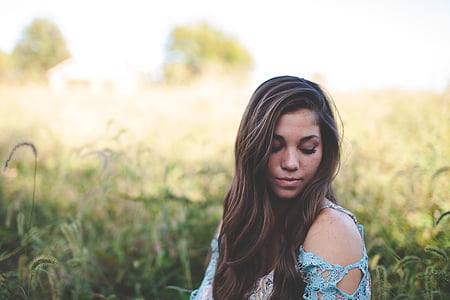 woman with blue cold-shouldered blouse sitting near green grass during daytime thumbnail