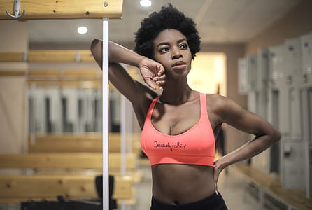 Young Adult African woman in peach sports bra posing in a dressing room of gym thumbnail