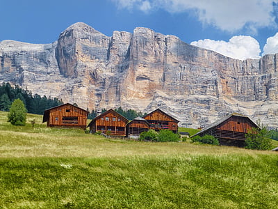 five brown wooden houses beside mountain under blue sky at daytime thumbnail