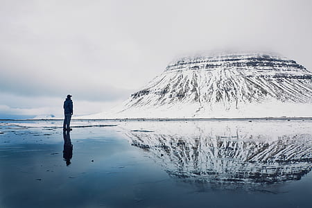 person standing on ice field near on snow mountain thumbnail