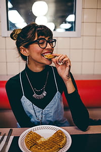 woman in black long-sleeved top eating waffle inside restaurant thumbnail