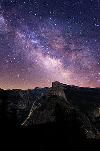 timelapse photography of rocky mountain under sky with stars thumbnail