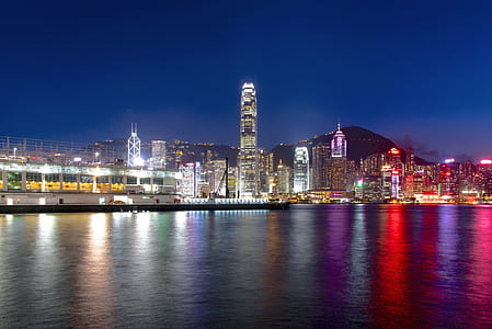 lightened city buildings near body of water at night time thumbnail