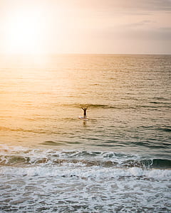 man riding blue surfboard taken at sunset thumbnail