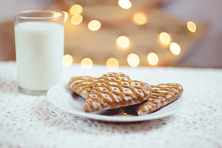 baked cookies on white ceramic saucer beside clear glass cup filled with white liquid thumbnail
