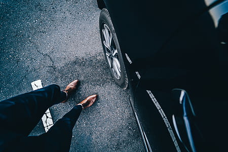 person wearing brown dress shoes near black car thumbnail