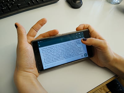 person holding black Android smartphone on top of white desk thumbnail