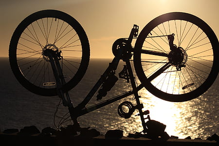 silhouette photography of bike near body of water thumbnail
