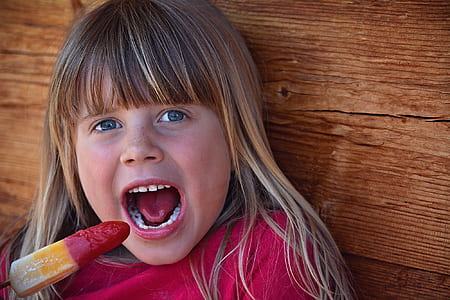 girl leaning on wooden surface while eating popsicle thumbnail