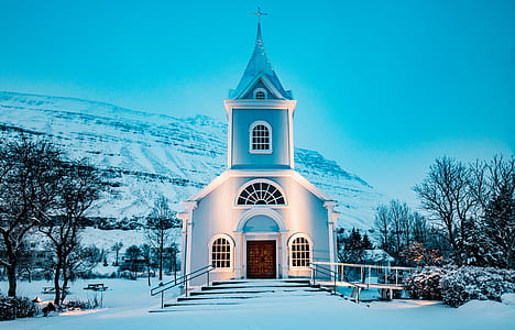 white concrete church between trees behind mountain thumbnail