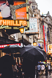 close up photo of two man holding black umbrellas thumbnail