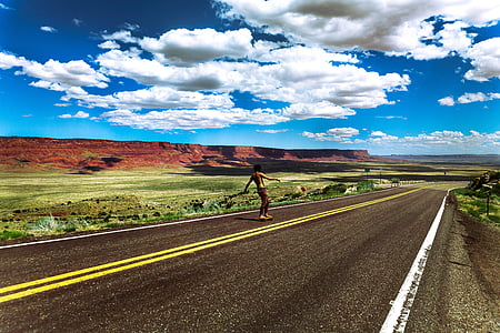 person skateboarding in the middle of the road beside grasss thumbnail