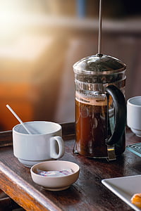 full filled coffee press beside coffee cup on brown wooden table thumbnail