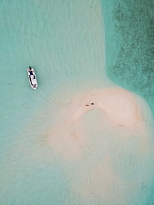 aerial photography of boat on calm water near island thumbnail