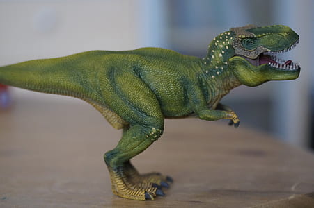 green dinosaur figurine on brown table thumbnail