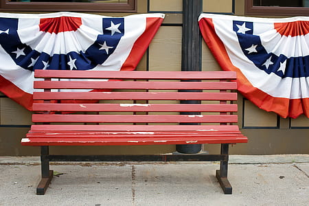 red wooden bench beside brown wall two flags thumbnail