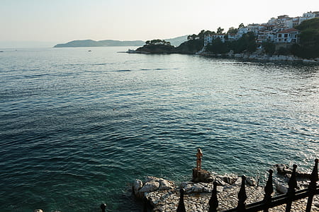 person standing on brown rock near seashore at day time thumbnail