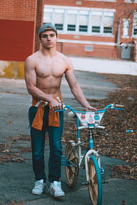 man standing beside teal and white BMX bike thumbnail