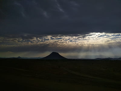 silhouette of mountain under white cloudy sky at with sun rays thumbnail
