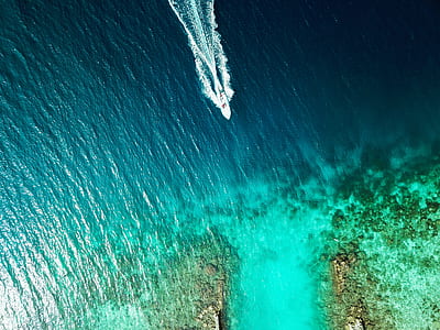 aerial photography of a boat near coastal rocks thumbnail