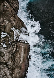 body of water beside brown mountain thumbnail
