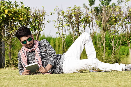 Man in White Pants Wearing Sunglasses Reading Book thumbnail