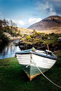 white and green wooden boat near calm grey body of water and mountain at daytime thumbnail