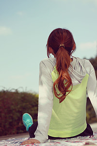 woman in grey and green hoodie sitting on mat during daytime thumbnail