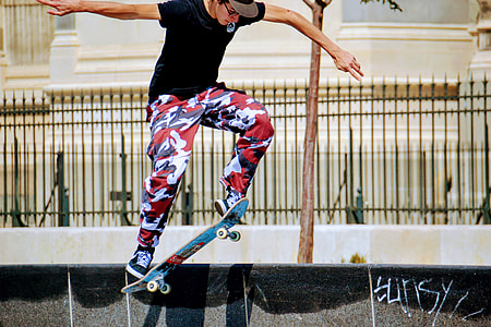 photo of man wearing black shirt and red-and-white pants skateboarding along street thumbnail