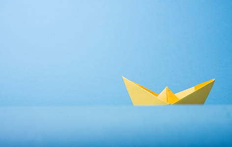 yellow paper boat on blue water thumbnail