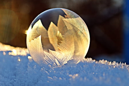 shallow focus of clear glass ornament on snow thumbnail