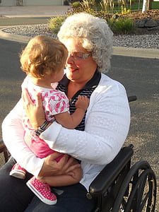 woman sitting on wheelchair carrying girl thumbnail