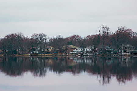 white and grey houses near body of water under cloudy sky during daytime thumbnail