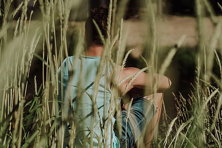 man sitting on grass near body of water thumbnail