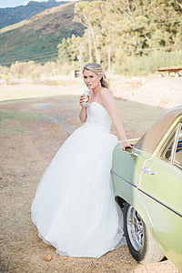 woman in white wedding dress sitting on car tailgate thumbnail