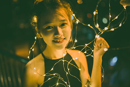 girl holding string light selective focus photography thumbnail