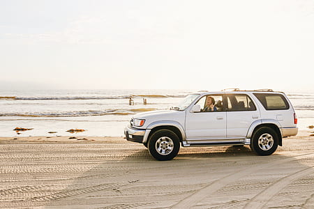 photo of white parked sport utility vehicle with woman inside near shoreline thumbnail