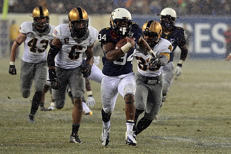 men running towards man holding football thumbnail