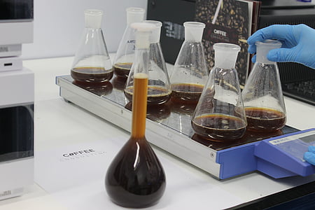 several clear glass Erlenmeyer's flasks with brown fluid on white table thumbnail