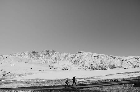 two people walking near snowy mountain thumbnail