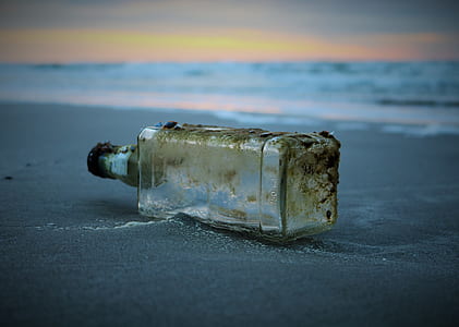 clear glass bottle on sand near seashore thumbnail
