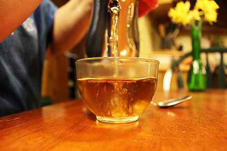 person pouring tea on teacup on table thumbnail
